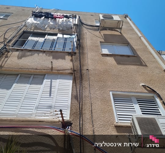 מזגנים מותקנים על קיר בניין עם חוטים חשמליים